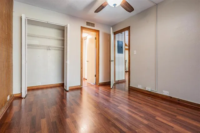 an empty room with wooden floor and a ceiling fan