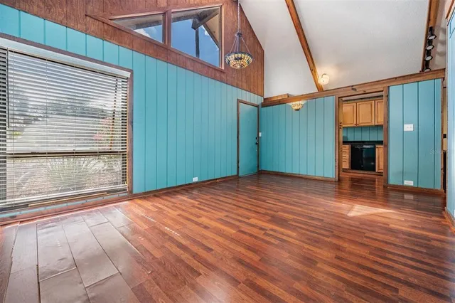 a view of empty room with wooden floor and fan