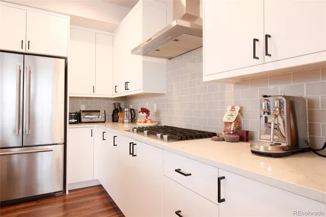 a kitchen with a refrigerator and white cabinets