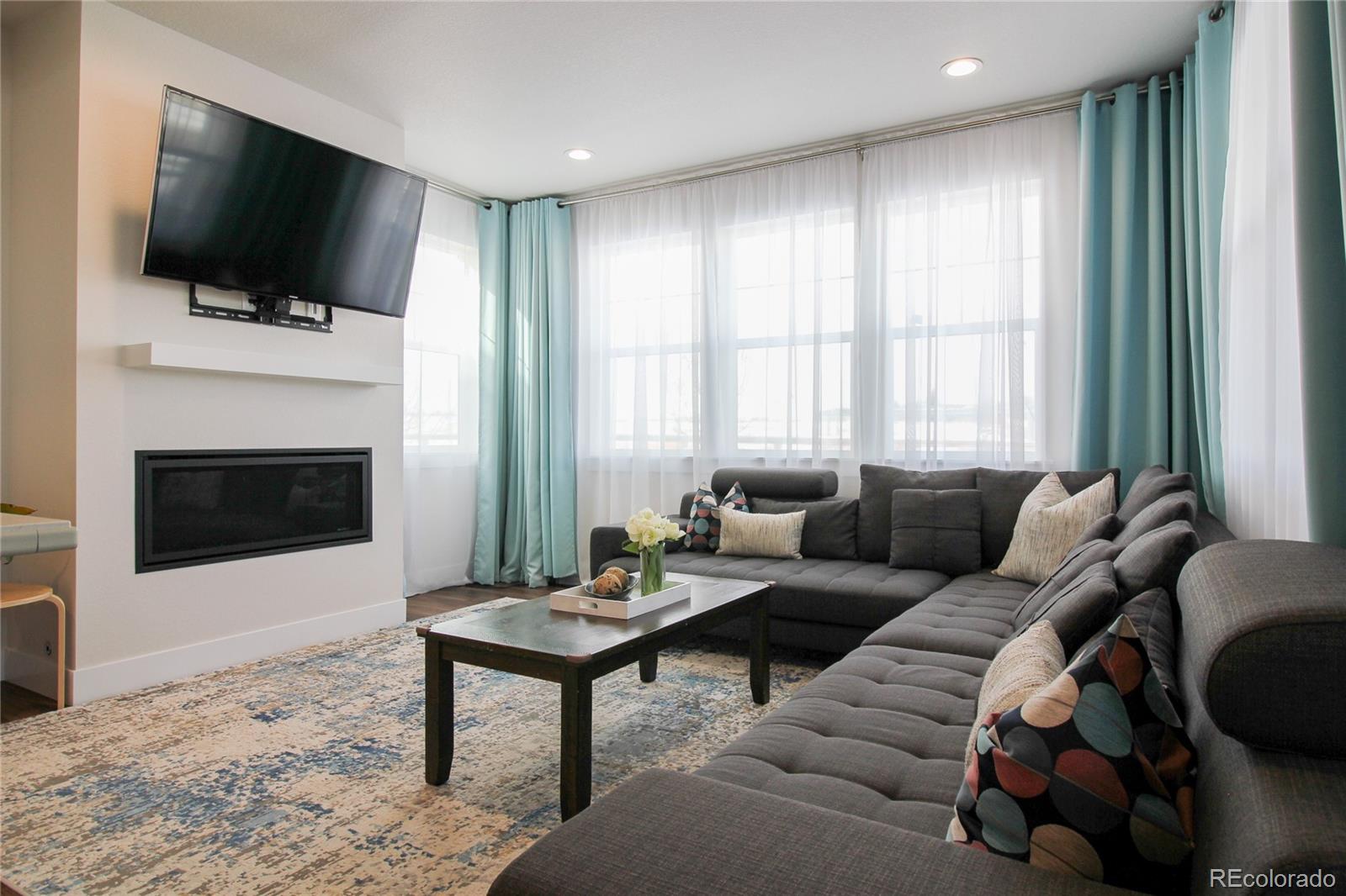 10394 Detroit Street Denver, CO 80229 - Photo 15 of 50 a living room with furniture a flat screen tv and a fireplace