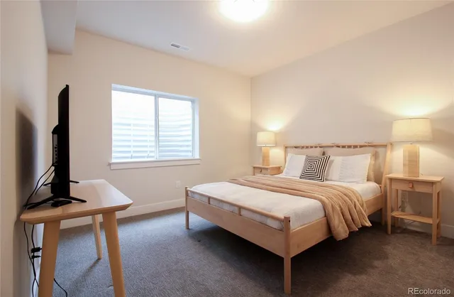 a bedroom with a bed table chair and a window