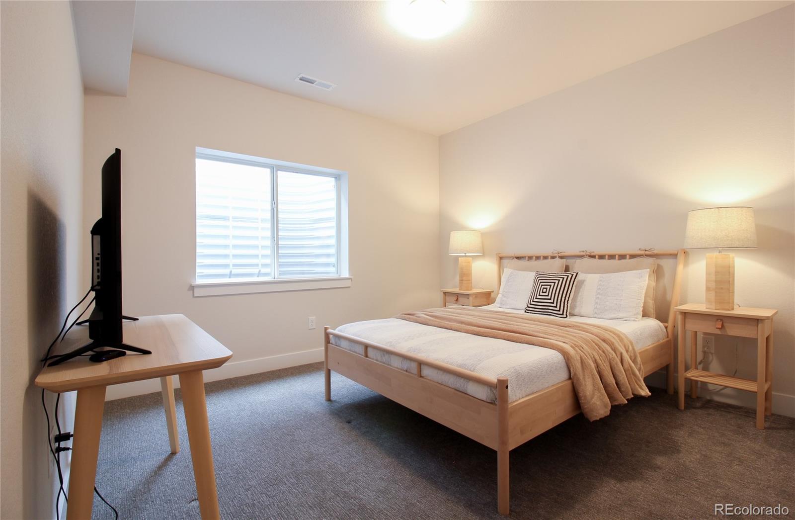 10394 Detroit Street Denver, CO 80229 - Photo 34 of 50 a bedroom with a bed table chair and a window