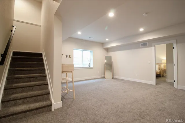 a view of an empty room with wooden floor and stairs