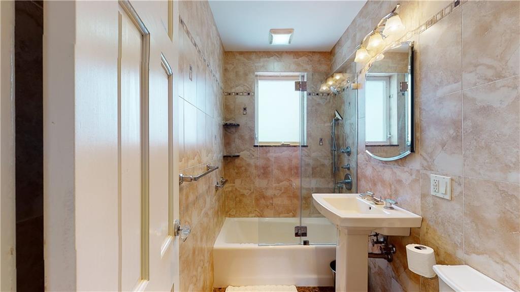 83 Gravesend Neck Road Brooklyn, NY 11223 - Photo 13 of 27 a bathroom with a sink a mirror and a bathtub