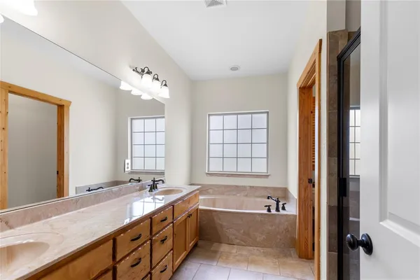 a bathroom with a granite countertop tub sink and mirror