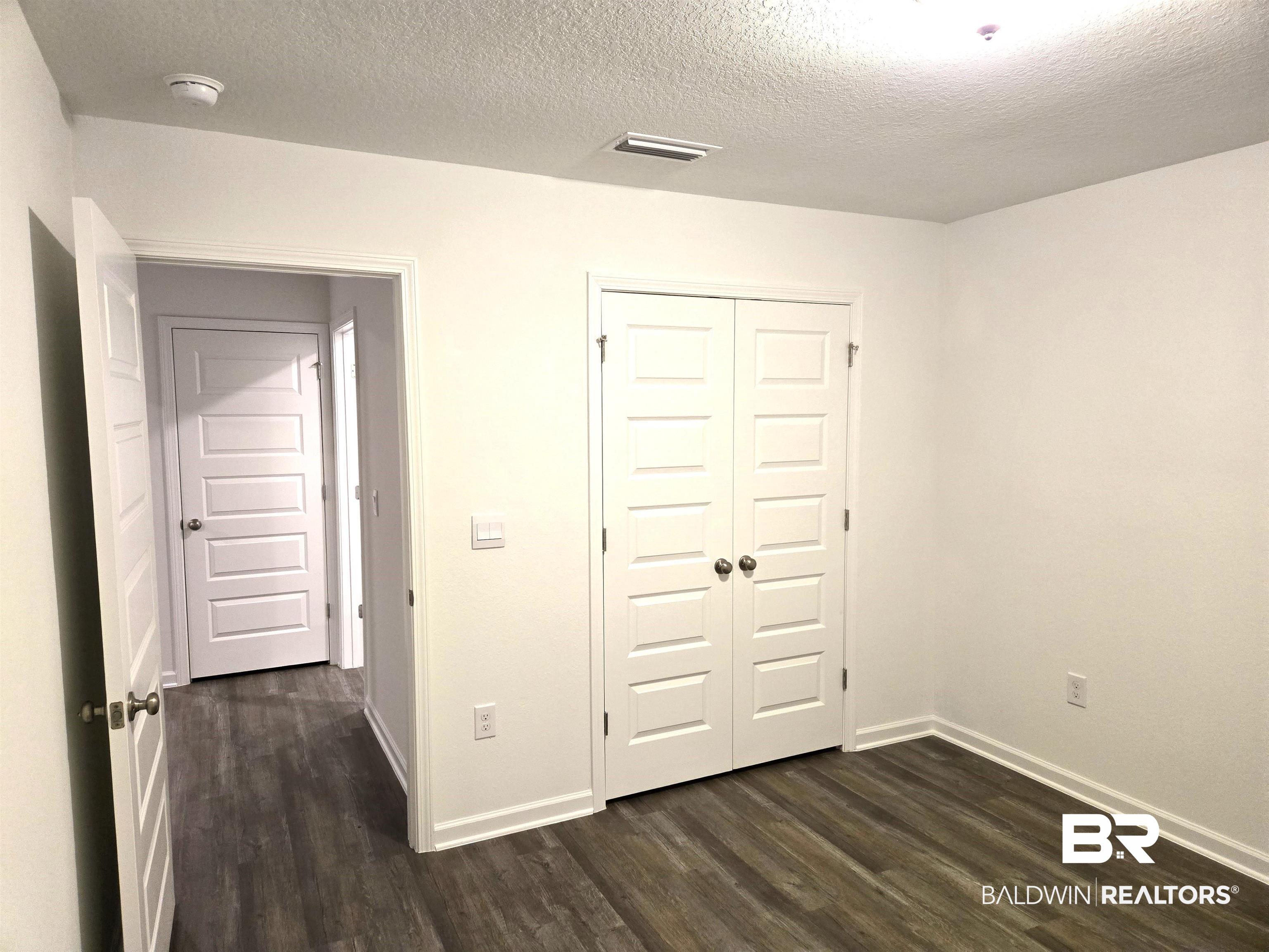 24321 Ringneck Loop Elberta, AL 36530 - Photo 21 of 39 Unfurnished bedroom featuring a textured ceiling, dark hardwood / wood-style floors, and a closet