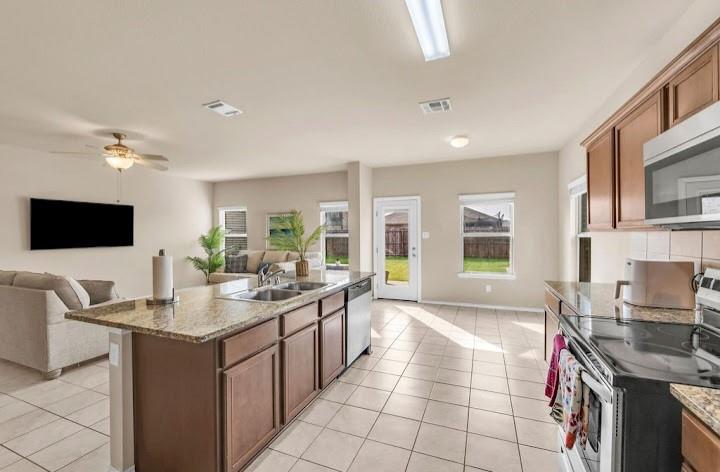 2315 Julia Lane Forney, TX 75126 - Photo 35 of 35 Kitchen with stainless steel appliances, open floor plan, light stone countertops, a kitchen island with sink, and light tile patterned floors