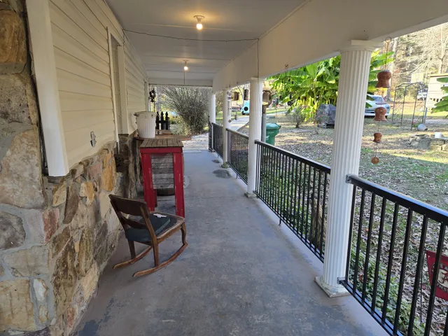 a view of a house with large trees and a car parked beside it