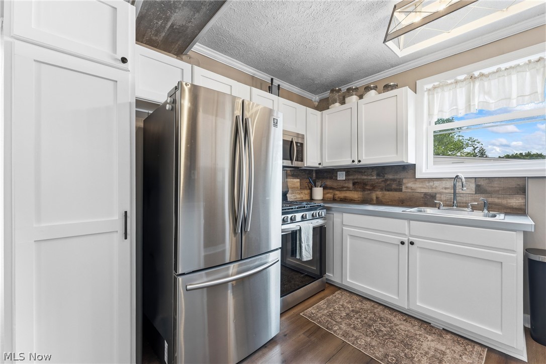 258 Randolph Road Mogadore, OH 44260 - Photo 15 of 49 Kitchen featuring a stainless steel refrigerator, white cabinetry, a wood-finish backsplash, and light-colored countertops