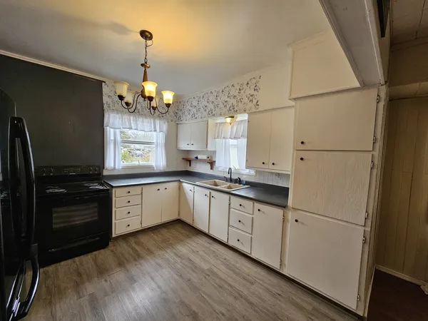 a large kitchen with granite countertop a refrigerator a stove a sink dishwasher a dining table and chairs with wooden floor