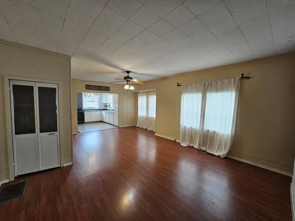 an empty room with wooden floor and windows
