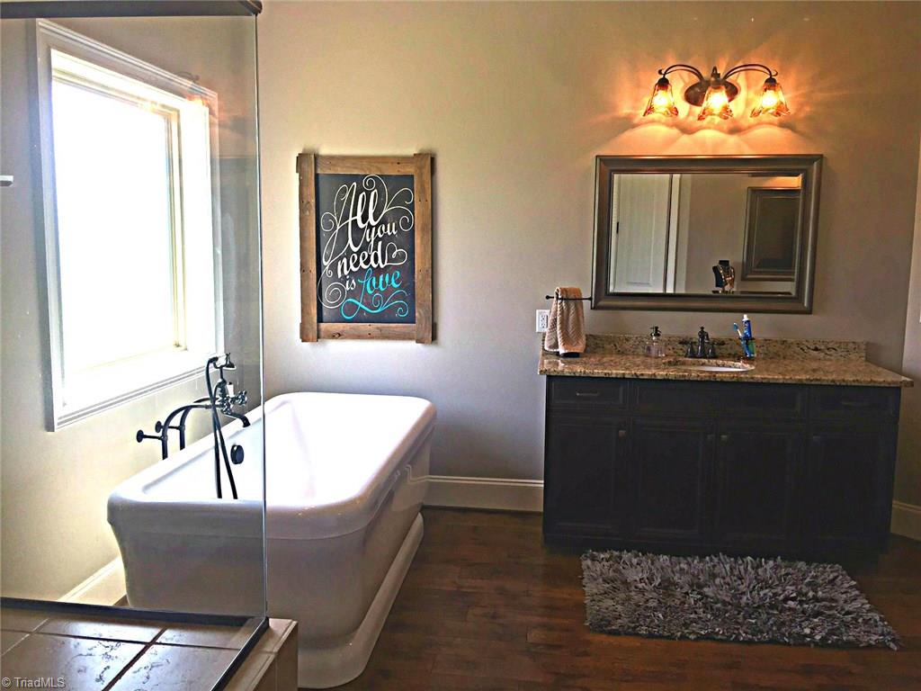 5849 Pepper Road Oak Ridge, NC 27310 - Photo 15 of 28 Master bath with his and hers, large tiled shower, stand alone tub and wood floors