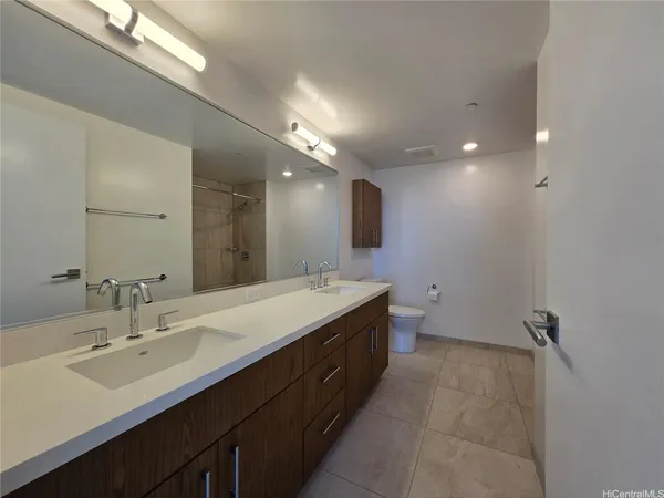a bathroom with a double vanity sink and mirror with toilet