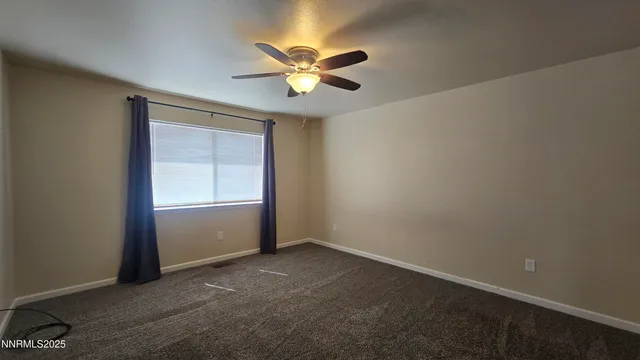 an empty room with a window and a fan