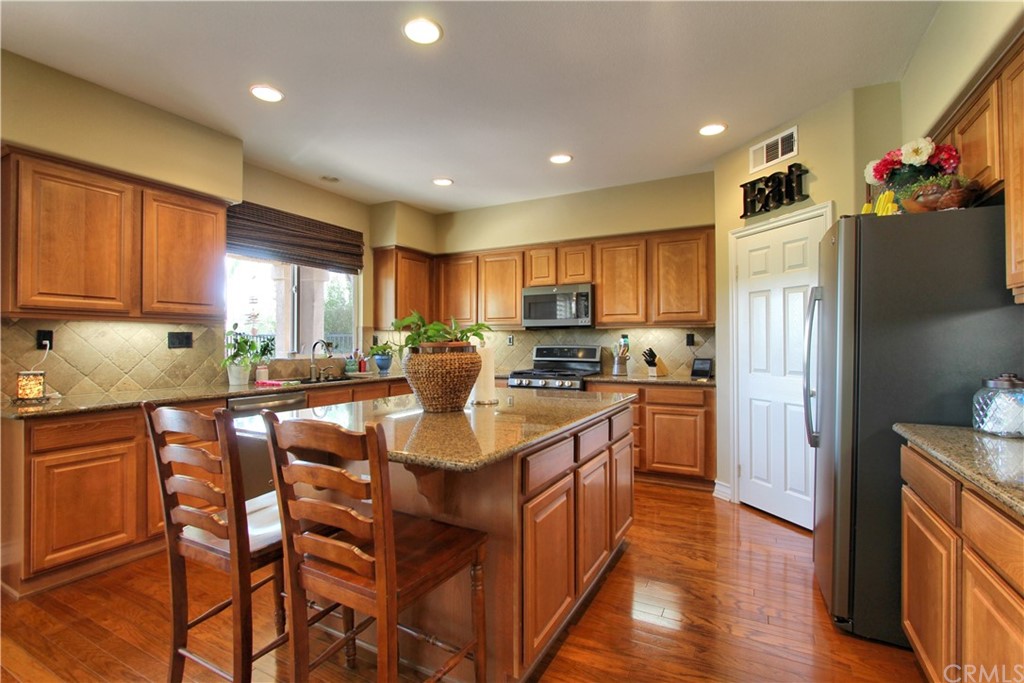 35107 Hogan Drive Beaumont, CA 92223 - Photo 8 of 42 a kitchen with stainless steel appliances granite countertop a refrigerator a sink dishwasher a stove and white countertops with wooden floor