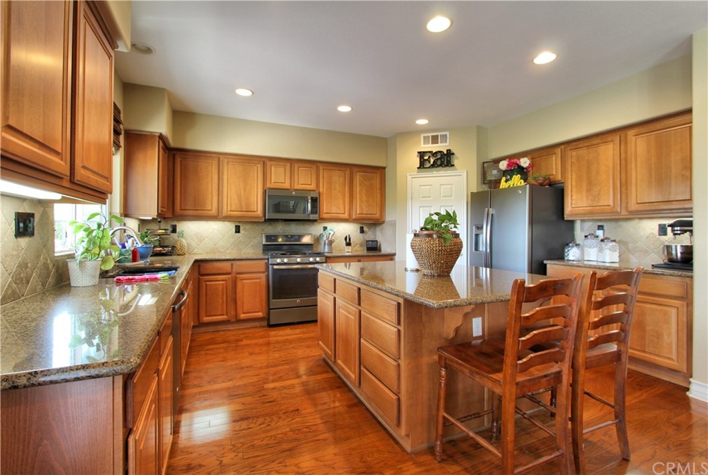 35107 Hogan Drive Beaumont, CA 92223 - Photo 9 of 42 a kitchen with stainless steel appliances granite countertop a refrigerator a stove top oven a sink dishwasher and cabinets with wooden floor