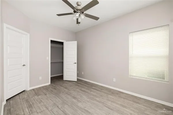 an empty room with wooden floor closet and windows