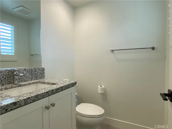 a bathroom with a granite countertop sink toilet and a mirror