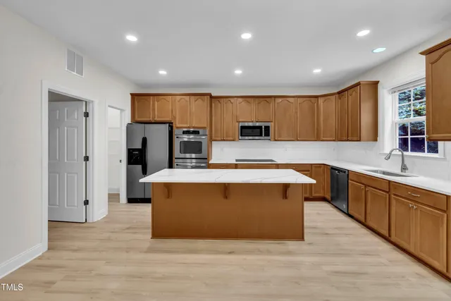 a large kitchen with stainless steel appliances a large counter top a stove a refrigerator and a sink