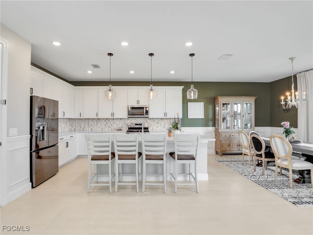 20179 Napa Loop Estero, FL 33928 - Photo 12 of 49 a large kitchen with white cabinets and stainless steel appliances
