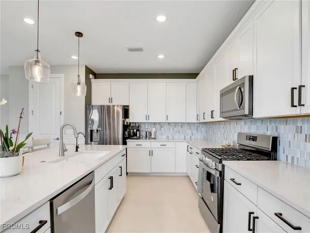a kitchen with a sink stainless steel appliances and white cabinets