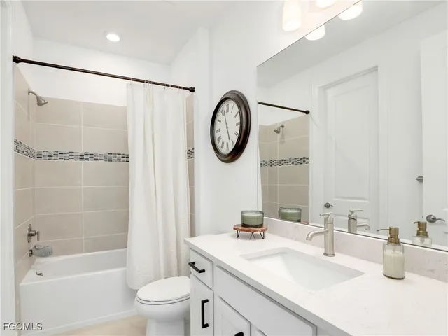 a bathroom with a bathtub shower sink vanity mirror and toilet