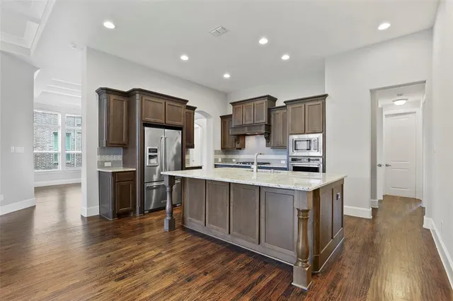a kitchen with stainless steel appliances a sink cabinets and wooden floor