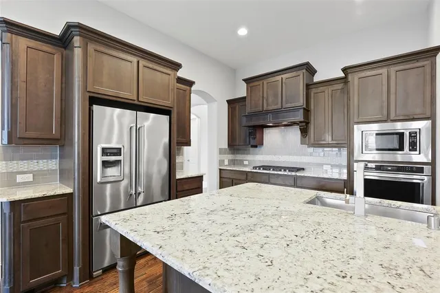 a kitchen with stainless steel appliances kitchen island granite countertop a refrigerator stove and oven