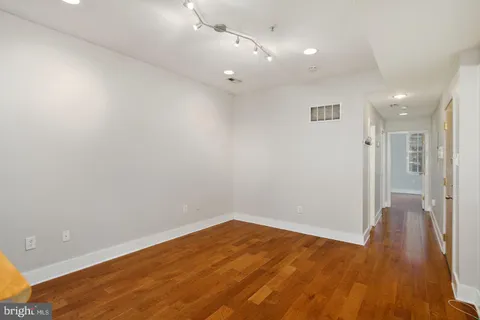 an empty room with wooden floor and a ceiling fan