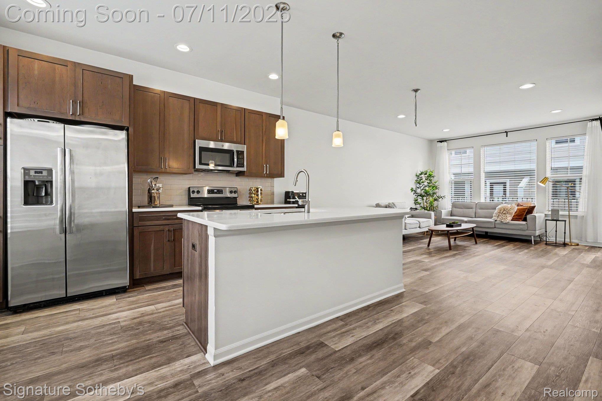 2500 Normandy Road, Unit 40 Royal Oak, MI 48073 - Photo 14 of 26 Open-concept living space featuring wood-finish flooring, a kitchen island with pendant lighting, stainless steel appliances, recessed lighting, and large windows