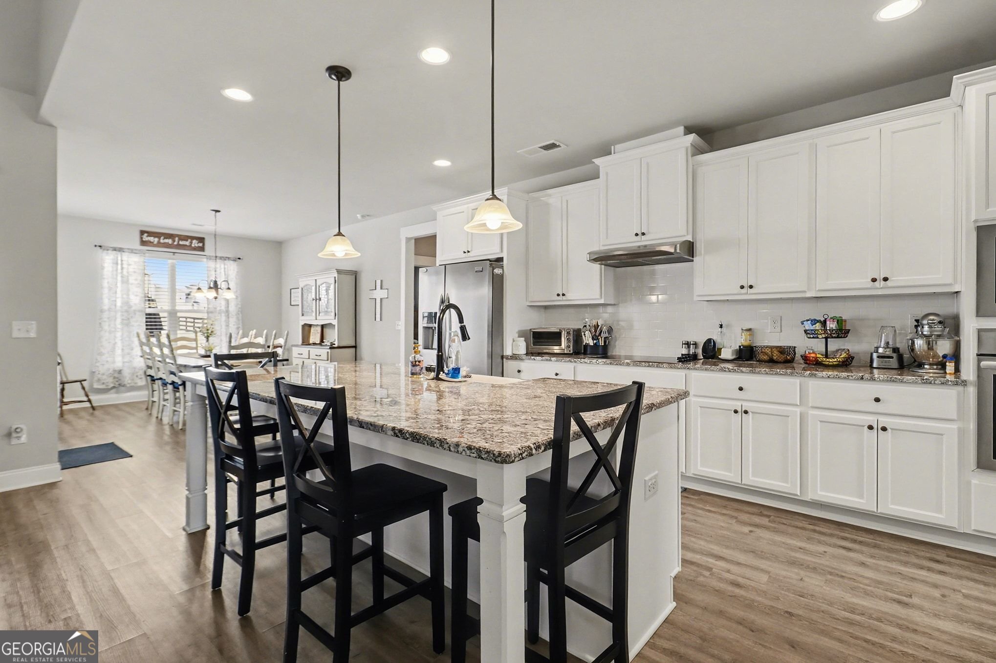 9 Union Street Newnan, GA 30263 - Photo 14 of 31 a kitchen with stainless steel appliances kitchen island granite countertop a table chairs and wooden cabinets