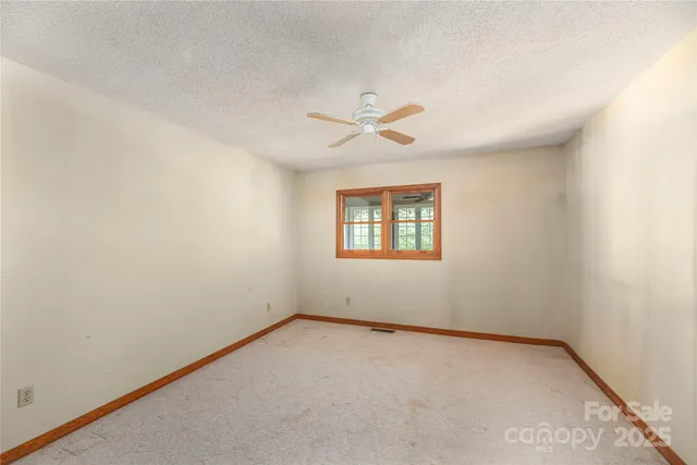 an empty room with a window and a ceiling fan