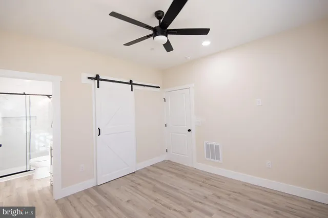 a view of a room with wooden floor and a ceiling fan