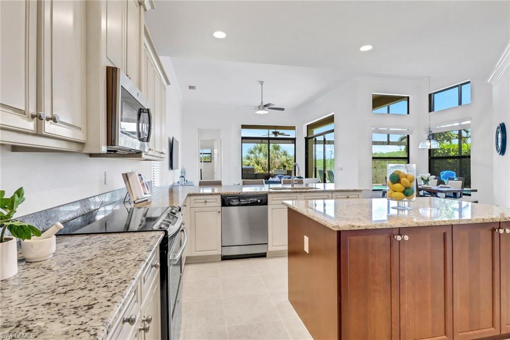 3260 Atlantic Circle Naples, FL 34119 - Photo 11 of 50 a kitchen with kitchen island granite countertop a sink cabinets and stainless steel appliances