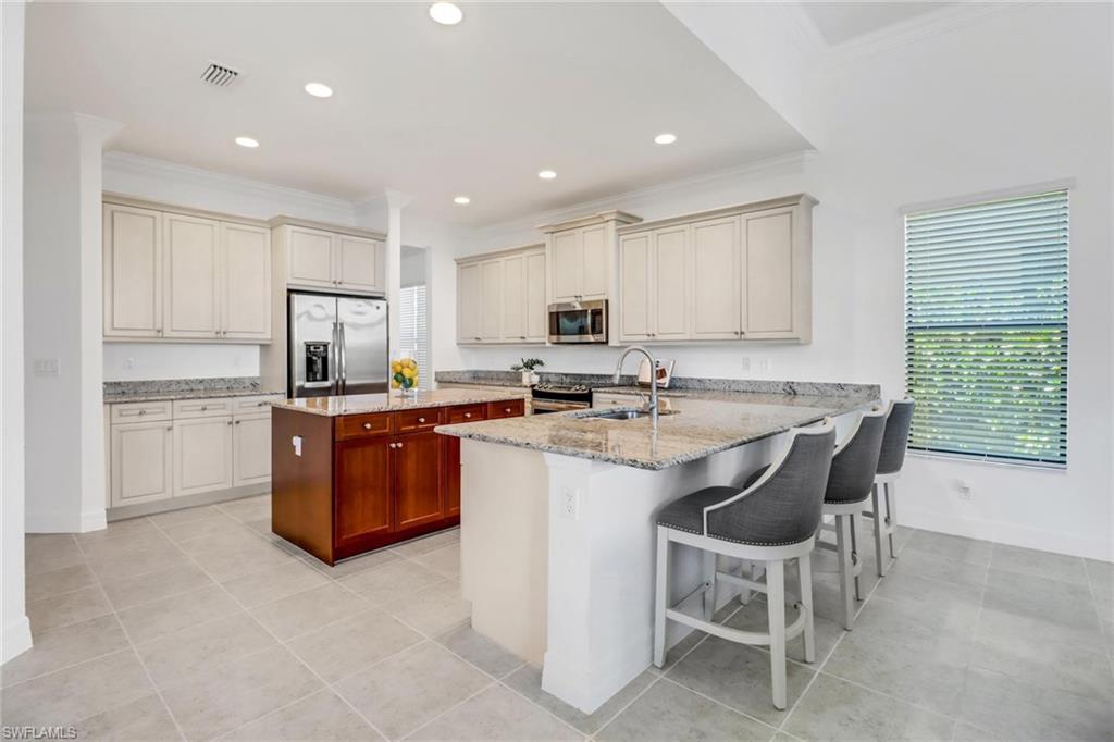 3260 Atlantic Circle Naples, FL 34119 - Photo 13 of 50 a kitchen with kitchen island granite countertop a sink counter top space appliances and cabinets