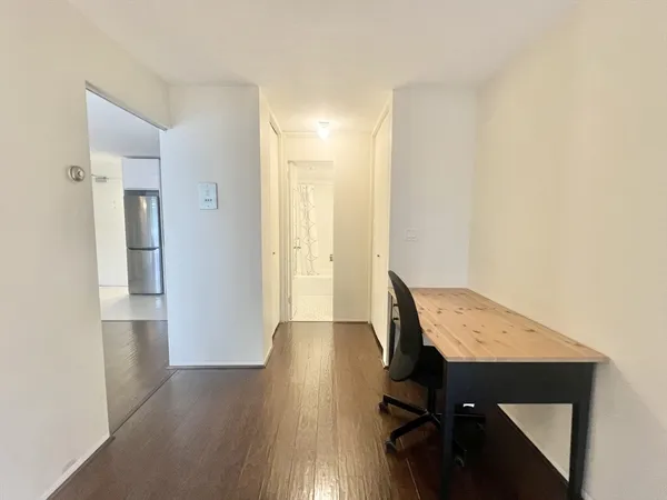 a view of a hallway with wooden floor and closet