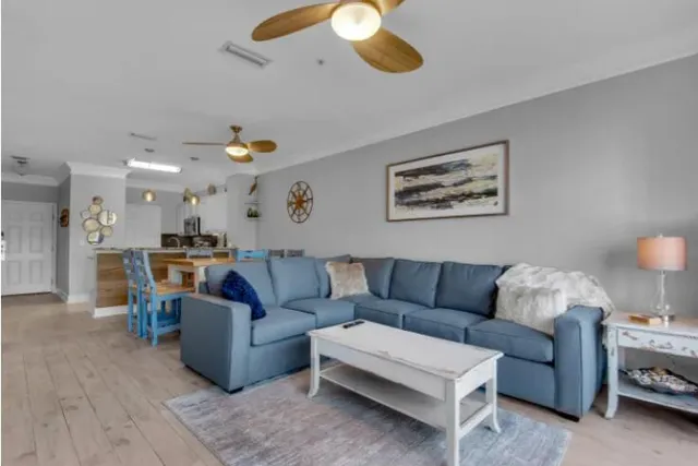 a living room with furniture kitchen view and a chandelier