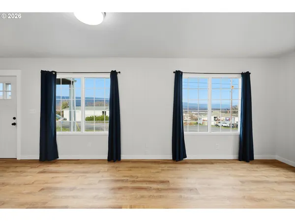 a view of an empty room with wooden floor and windows
