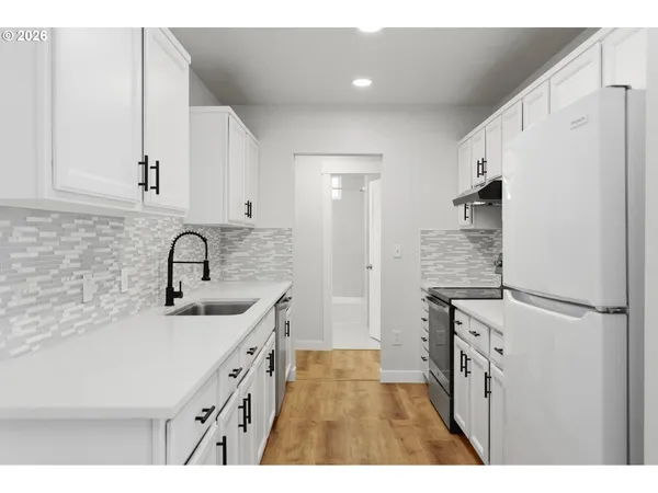 a kitchen with white cabinets and refrigerator