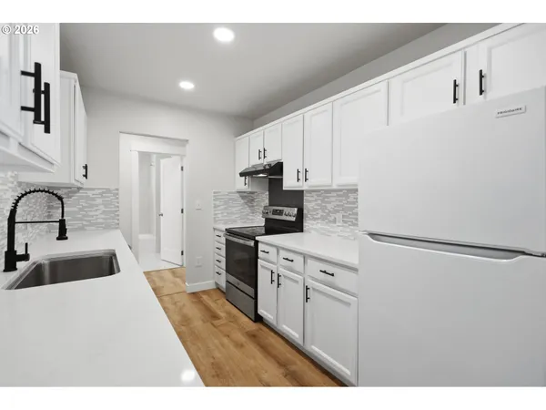 a kitchen with stainless steel appliances a refrigerator sink and white cabinets