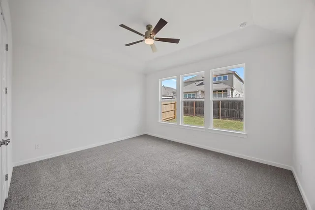 an empty room with windows and ceiling fan