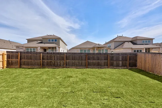 a view of a house with a yard and wooden fence