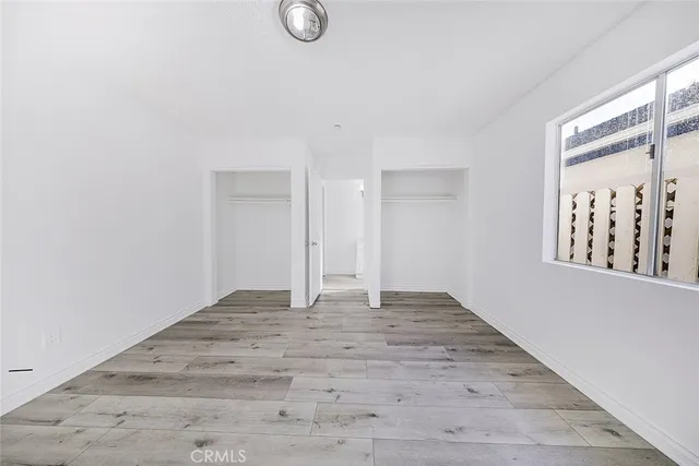 a view of an empty room with window and hardwood floor