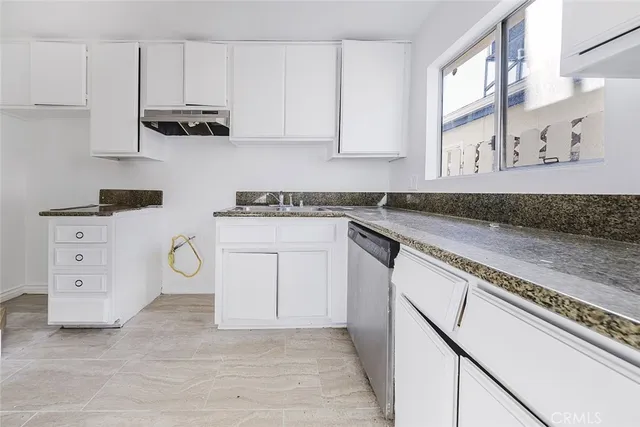 a kitchen with stainless steel appliances granite countertop a stove a sink and a white cabinets