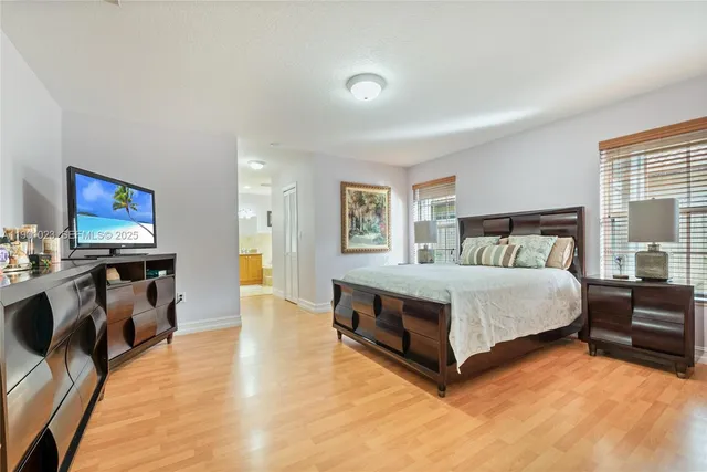 a spacious bedroom with a bed and a flat tv screen on dresser