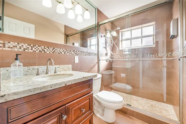 a bathroom with a granite countertop sink a toilet and a mirror