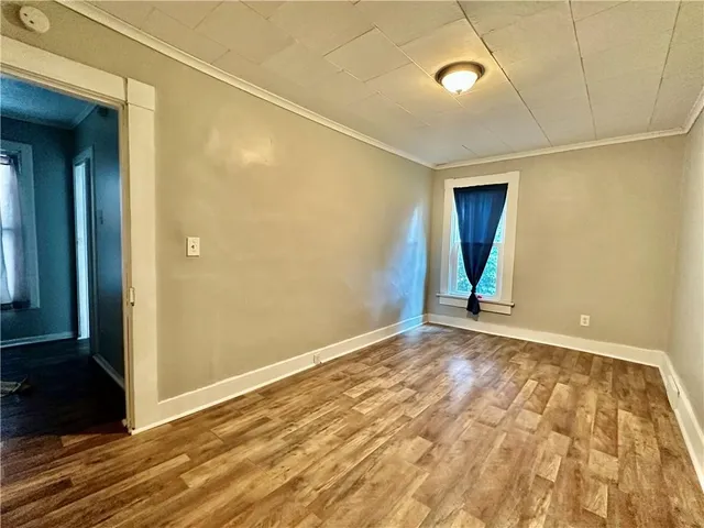 a view of an empty room with window and wooden floor