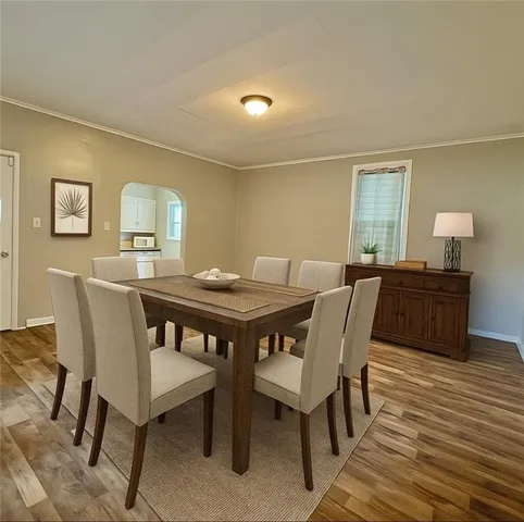 a view of an empty room with wooden floor and a bathroom