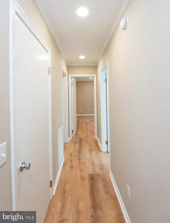 a view of a hallway with wooden floor and a bathroom