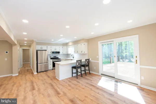 a open kitchen with stainless steel appliances granite countertop a stove top oven a sink dishwasher a dining table and chairs with wooden floor